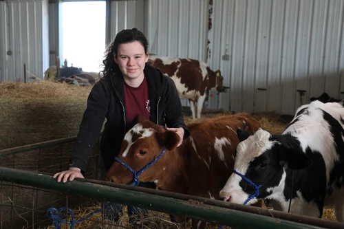 Woman smiling next to cows.